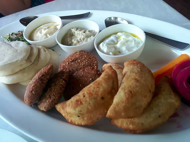 A mezze platter with falafel, hummus, tzatziki, baba ganoush, pita, and tabbouleh.