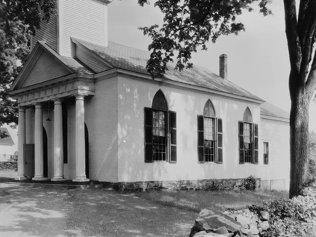 The exterior of a red brick church building with a white steeple.