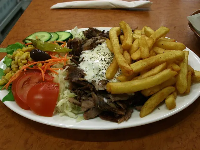 A plate of gyros meat with vegetables.