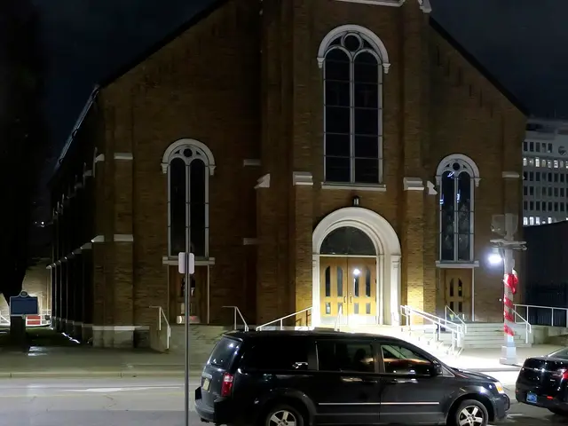 Exterior of Saint Alphonsus Church in Windsor, Ontario, a brick church with a tall steeple, photographed at night.
