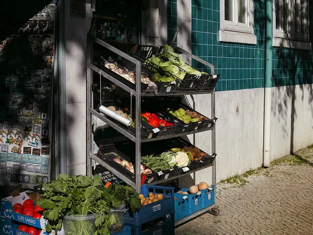 A wheeled produce display holding fresh vegetables outside a grocery shop on a cobblestone street in Lisbon