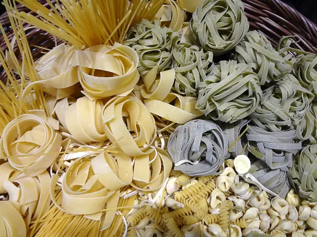 A variety of fresh and dry pasta shapes arranged together.