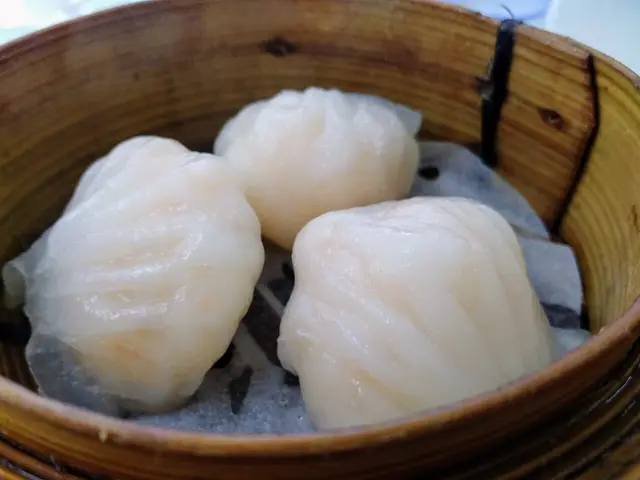 Three dim sum dumplings resting in a bamboo steamer basket.