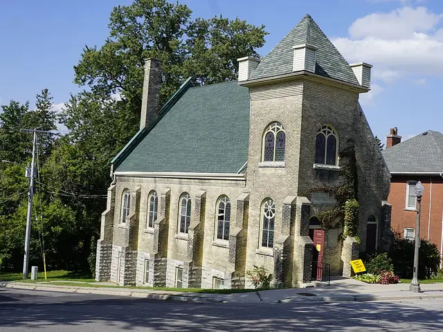 First Baptist Church in St. Marys, Ontario, a two-storey buff brick Baptist church with a corner bell tower and gothic-arched stained glass windows.