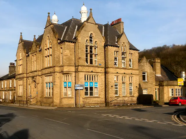 A Victorian-era stone building housing Holmfirth Adult Education Centre on a street corner in England.