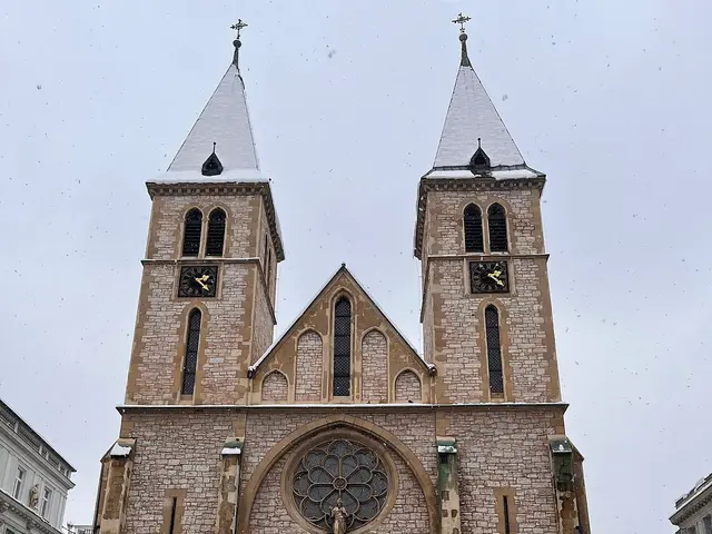 Exterior of Sarajevo Catholic Cathedral (Sacred Heart Cathedral), a twin-spired Gothic Revival cathedral dusted with snow.