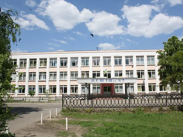 A pink and white multi-storey school building with a sign bearing the school's name above the entrance.