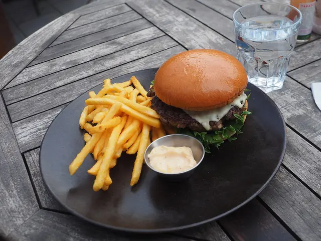 A beef burger with mushrooms and lettuce served at a restaurant table.