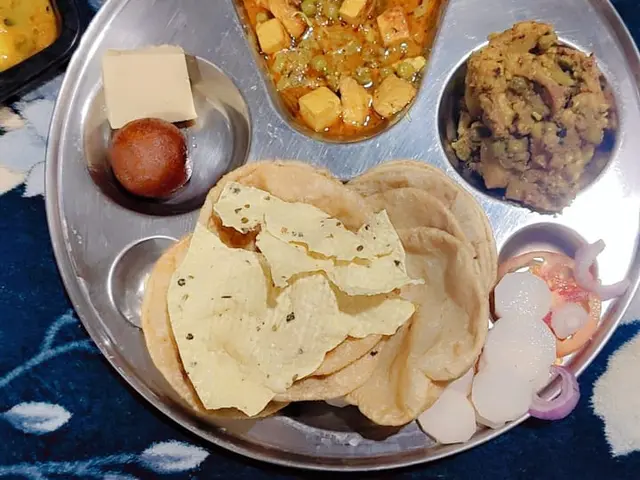 A home-style Indian thali with rice, bread, and several small dishes.