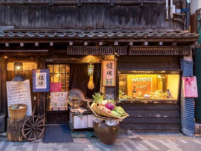 Illuminated restaurant facade with baskets of vegetables at the entrance in Yurakucho, Chiyoda, Tokyo.