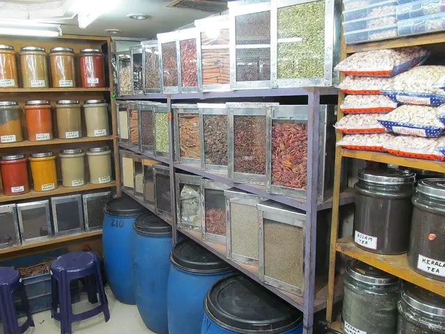 Interior of an Indian spice store with shelves of labeled spice jars, dried spices in bins, and tins of Assam and Kerala tea.