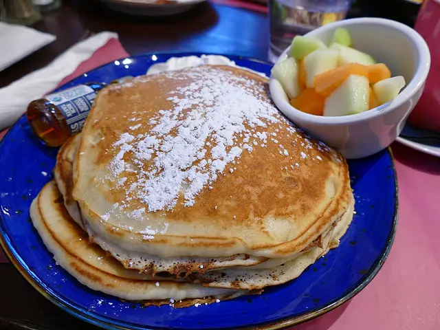 Buttermilk pancakes with fruit and maple syrup served at a diner.