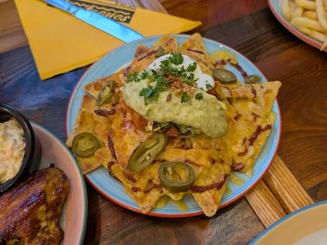 A plate of nachos topped with melted cheese, jalapenos, salsa, and guacamole from Montague's Tex-Mex.