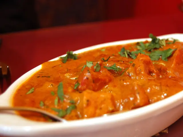 A bowl of chicken makhani, an orange-red Indian butter chicken curry.