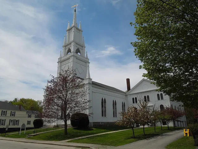 The exterior of a white wooden church building with a tall steeple.