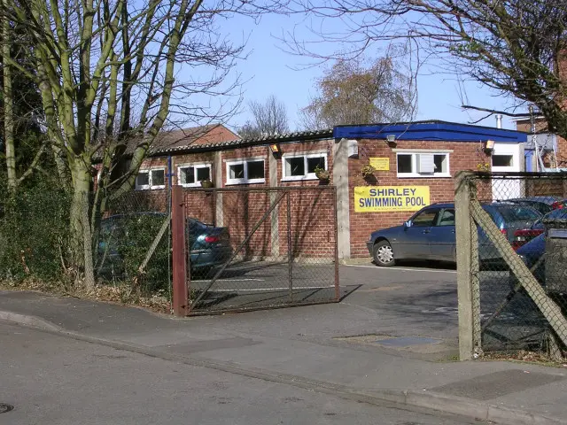 The brick exterior of a public swimming pool building, with no people visible.
