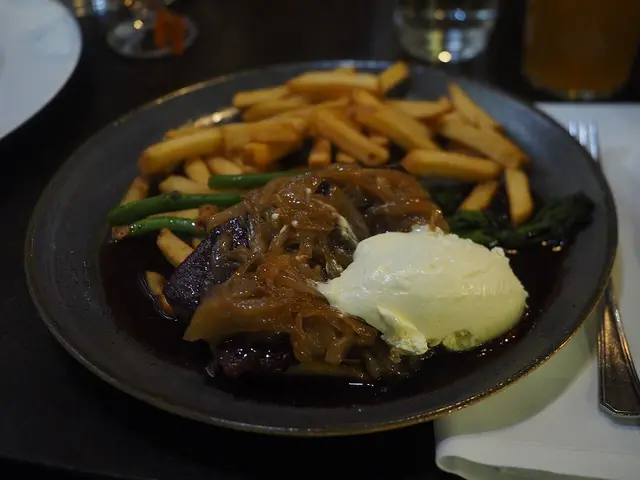 An onion-topped steak with fries and sour cream served at a restaurant table.