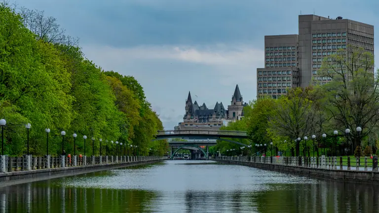 Le canal Rideau à Ottawa bordé d’arbres, avec le Château Laurier au loin